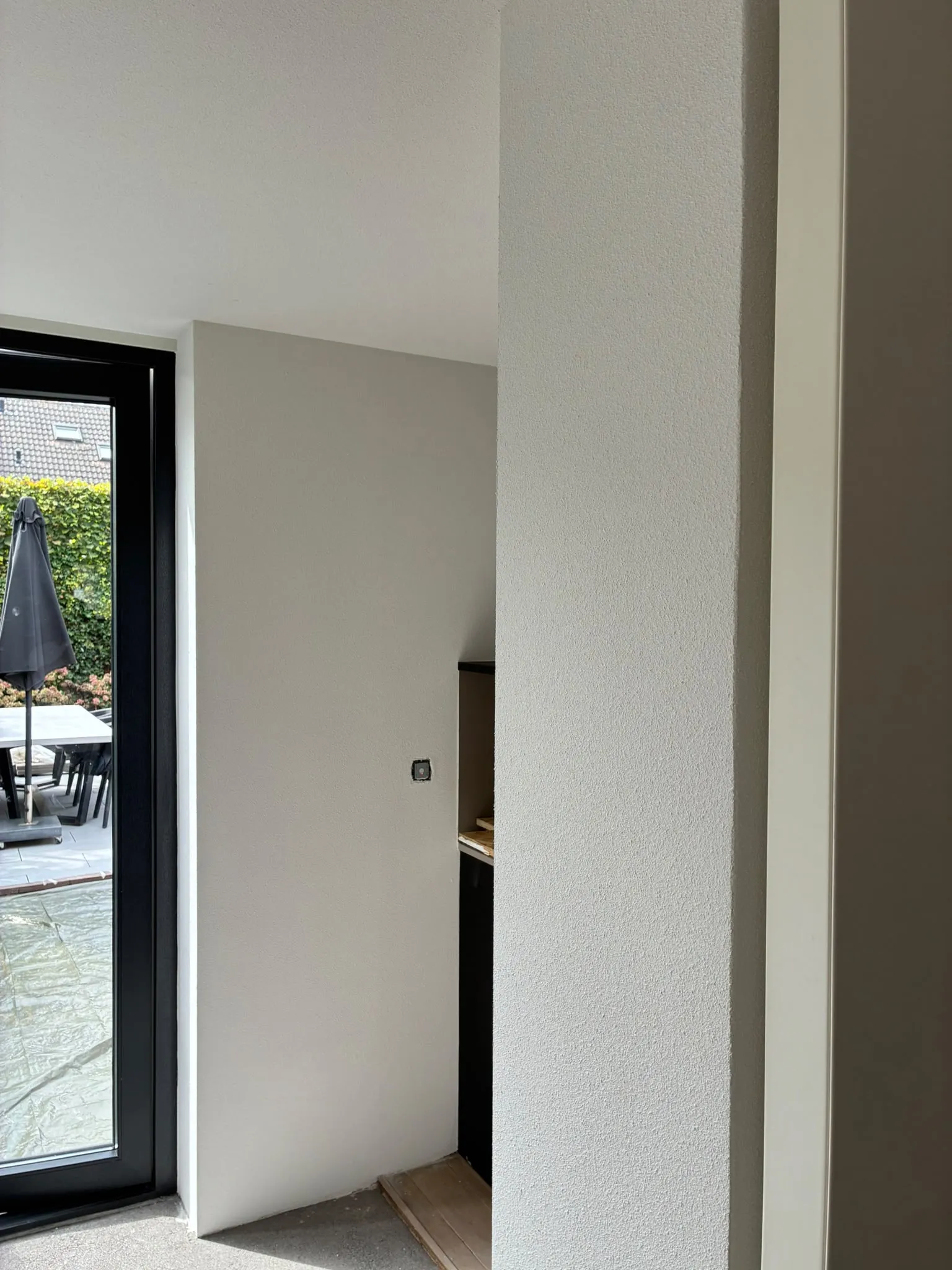 Strak gespoten hoek en pilaar in een lichte woonruimte